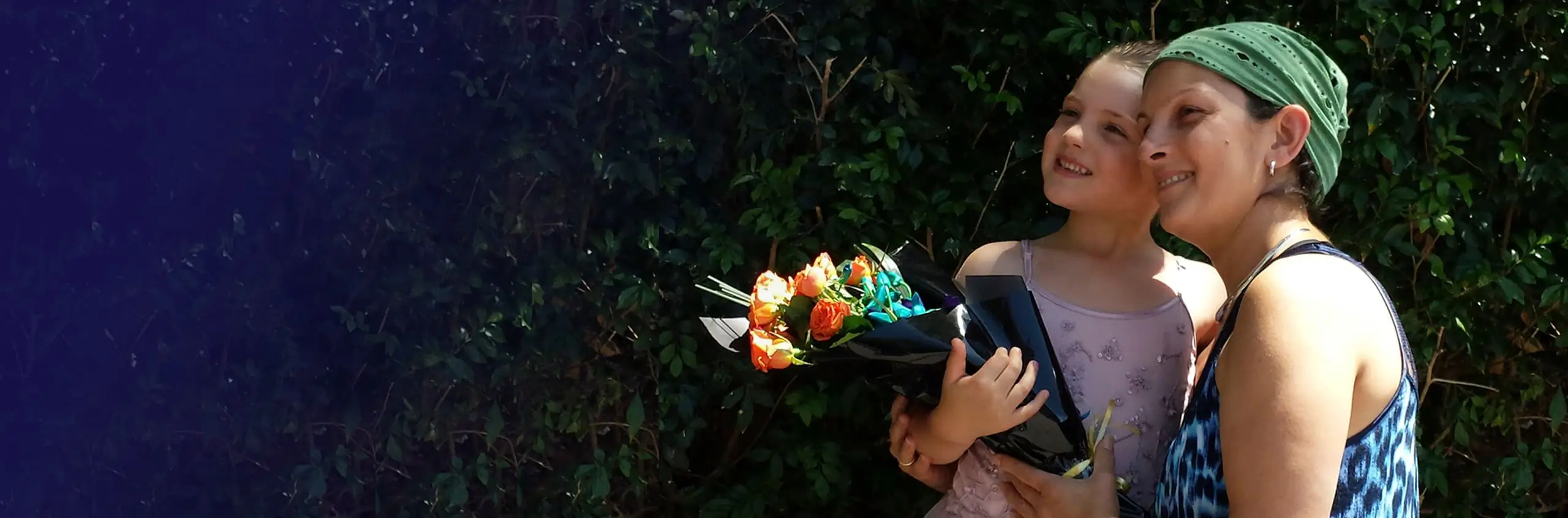 Jacqui and her daughter in a beautiful garden holding a rose bouquet