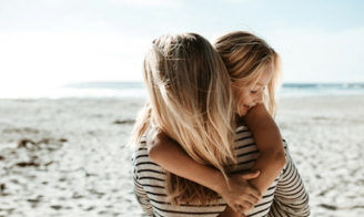 Mother and daughter embracing on the beach.