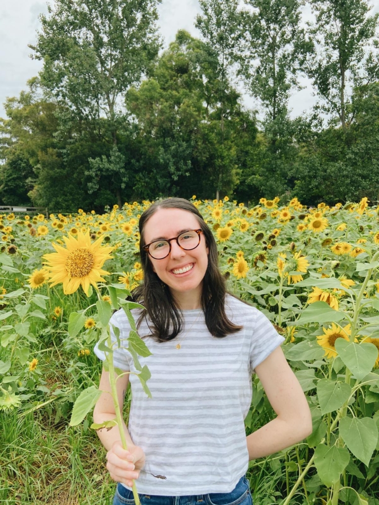 Sam holding a sunflower and smiling at the camera.